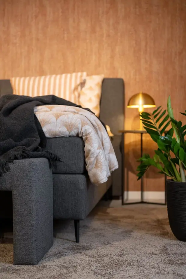 Donkergrijze boxspring met hoofdbord van Sleep Design tegen een warme wand